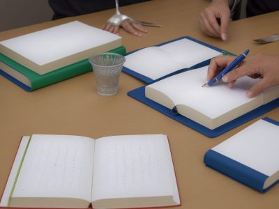 Crianças aprendendo o sistema braille em sala de aula, com livros e recursos adaptados para alfabetização inclusiva