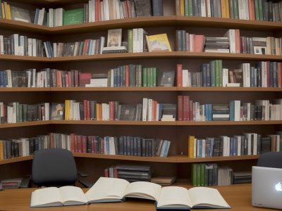 Imagem de uma biblioteca pública com pessoas usando computadores, lendo livros e participando de atividades, representando o uso da biblioteca e o acesso ao conhecimento.