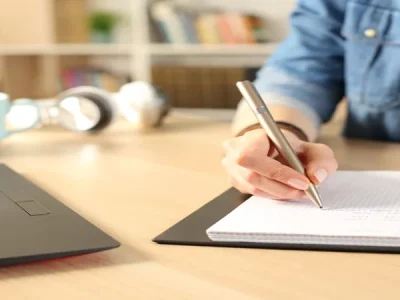 uma pessoa escrevendo em um caderno sobre curiosidades da língua portuguesa