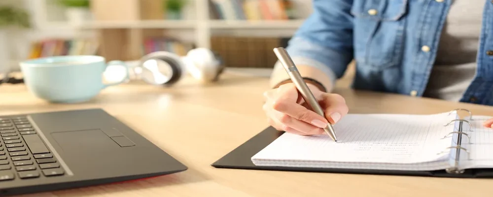 uma pessoa escrevendo em um caderno sobre curiosidades da língua portuguesa