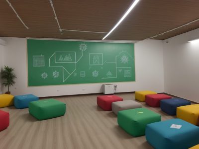 Professora auxiliando aluno com necessidades especiais em sala de aula durante curso de educação inclusiva, com recursos de apoio e ambiente acolhedor.