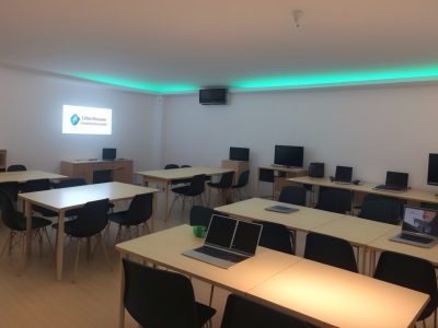 Estudantes aprendendo em um curso de informática básica, com computadores e materiais de estudo, mostrando o impacto na carreira.