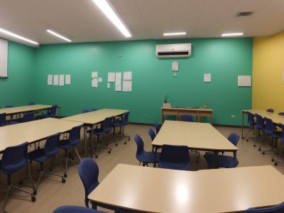 Imagem de uma sala de aula inclusiva com professor e alunos, demonstrando adaptação curricular e recursos pedagógicos na educação especial.