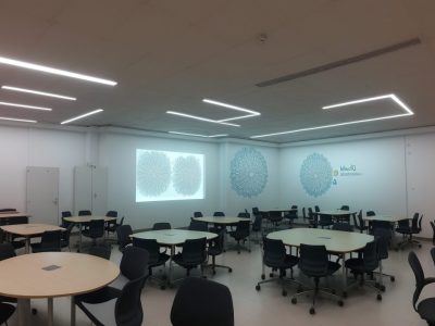 Ilustração de estudantes debatendo em uma sala de aula sobre os fundamentos da ciência política, com mapas e gráficos.