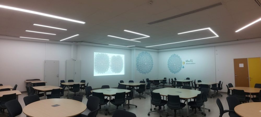 Ilustração de estudantes debatendo em uma sala de aula sobre os fundamentos da ciência política, com mapas e gráficos.