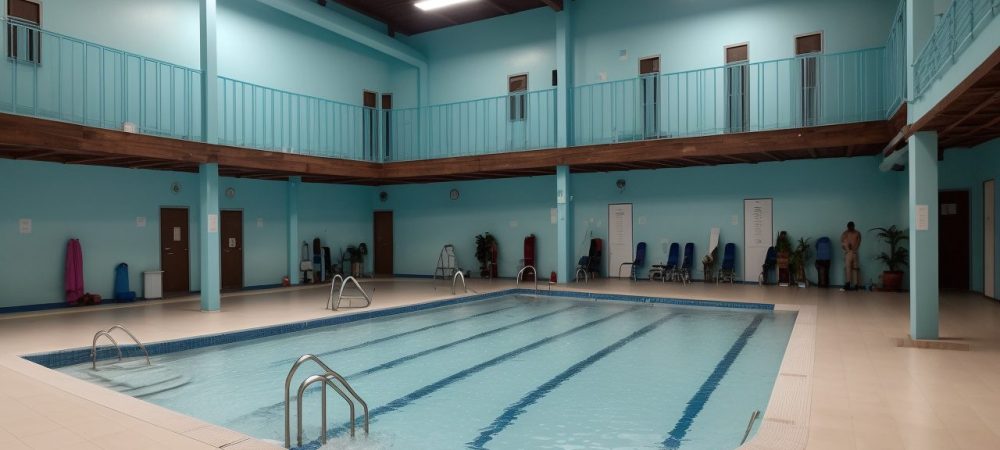 Aula de hidroginástica com pessoas de diferentes idades se exercitando na água, mostrando os benefícios para a saúde e bem-estar.