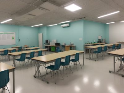 Sala de aula de química com professores e alunos realizando experimentos práticos sobre reações químicas