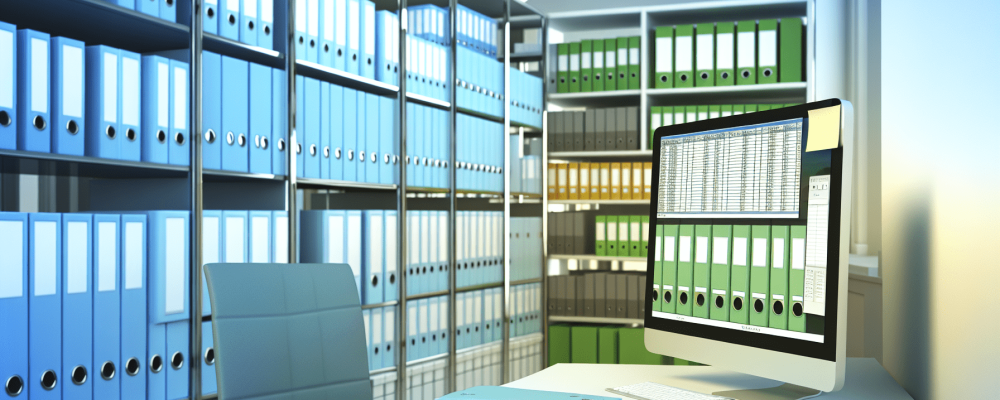 Escritório moderno com documentos digitalizados, pastas coloridas e tela de computador mostrando planilha de controle, em ambiente iluminado e organizado.