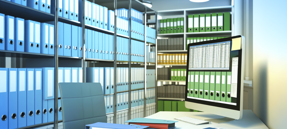 Escritório moderno com documentos digitalizados, pastas coloridas e tela de computador mostrando planilha de controle, em ambiente iluminado e organizado.