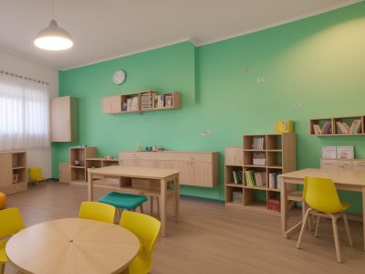 Alunos utilizando tablets e livros em uma sala de aula moderna de alfabetização e letramento.