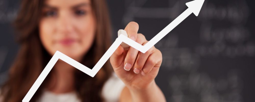 Uma mulher ao fundo desenhando na tela um gráfico de desempenho profissional