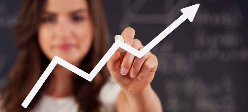 Uma mulher ao fundo desenhando na tela um gráfico de desempenho profissional