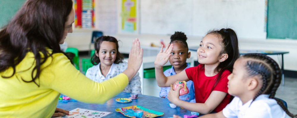diferença entre psicopedagogia e neuropsicopedagogia: professora trabalhando com alunos pequenos em sala de aula