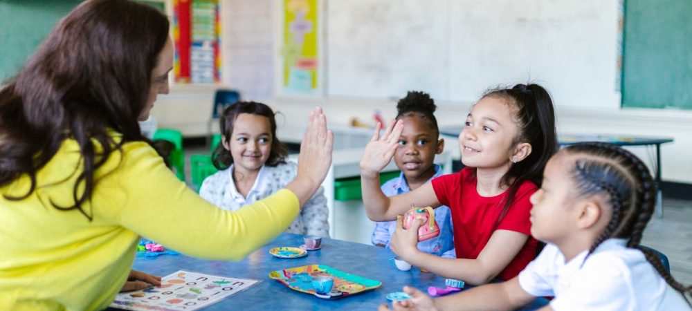 diferença entre psicopedagogia e neuropsicopedagogia: professora trabalhando com alunos pequenos em sala de aula