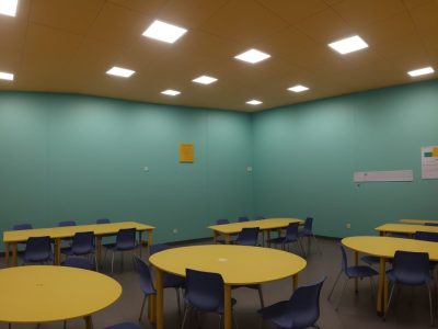 Sala de aula iluminada com alunos de diferentes habilidades colaborando, cercados por materiais acessíveis e tecnologia assistiva.