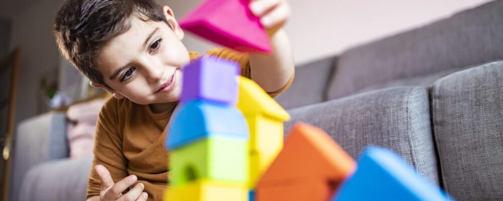 Funny boy playing with blocks at home