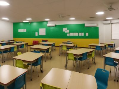 Pais e educadores reunidos em sala de aula vibrante, discutindo a importância da parceria escola-família