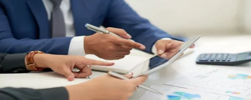pessoas-de-negocios-irreconheciveis-sentado-na-reuniao-com-graficos-olhando-e-apontando-para-tablet-1