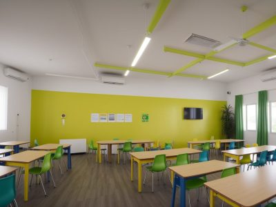 Alunos de diversas origens colaborando em uma sala de aula inclusiva, cheia de luz natural e arte colorida.