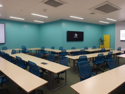 Equipe de profissionais de segurança do trabalho usando EPIs em treinamento público, discutindo normas regulamentadoras e estratégias de segurança.