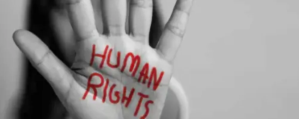 Mão de uma mulher virada para frente representando a luta da violação dos direitos humanos, escrita com caneta vermelho direitos humanos